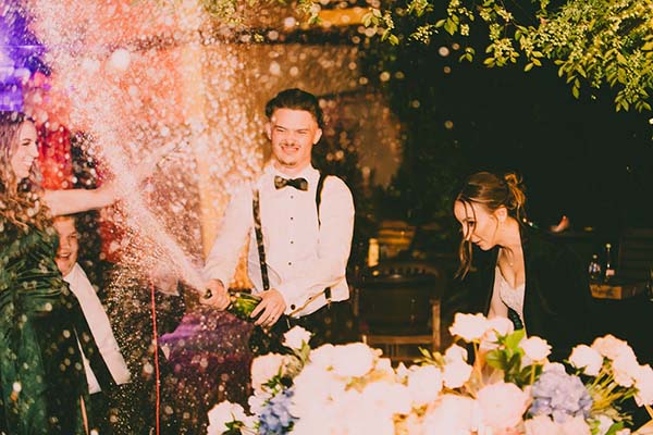 groom popping champagne at their wedding